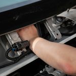 Close-up of mechanic hands repairing car electrical system, showcasing skill and precision.